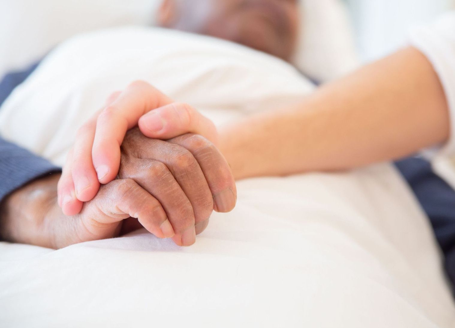 A comforting gesture as a hand holds another in a hospital setting, symbolizing care and support.